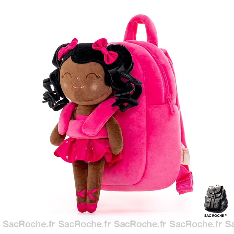 sac à dos de CP pour enfant , rose avec sur le devant une poupée en peluche d'une petite fille habillée en petite danseuse de ballet, c'est une jeune fille de couleur, elle est souriante et les yeux fermés