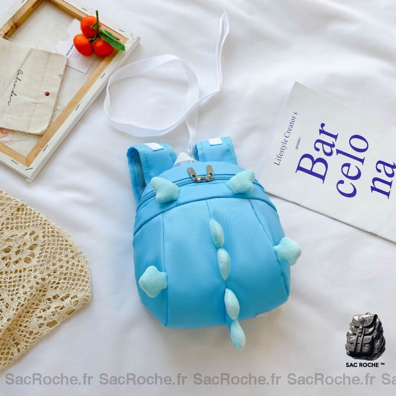 Sac à dos préscolaire forme dinosaure bleu avec un fond un lit blanc et un poster blanc avec des écritures bleu