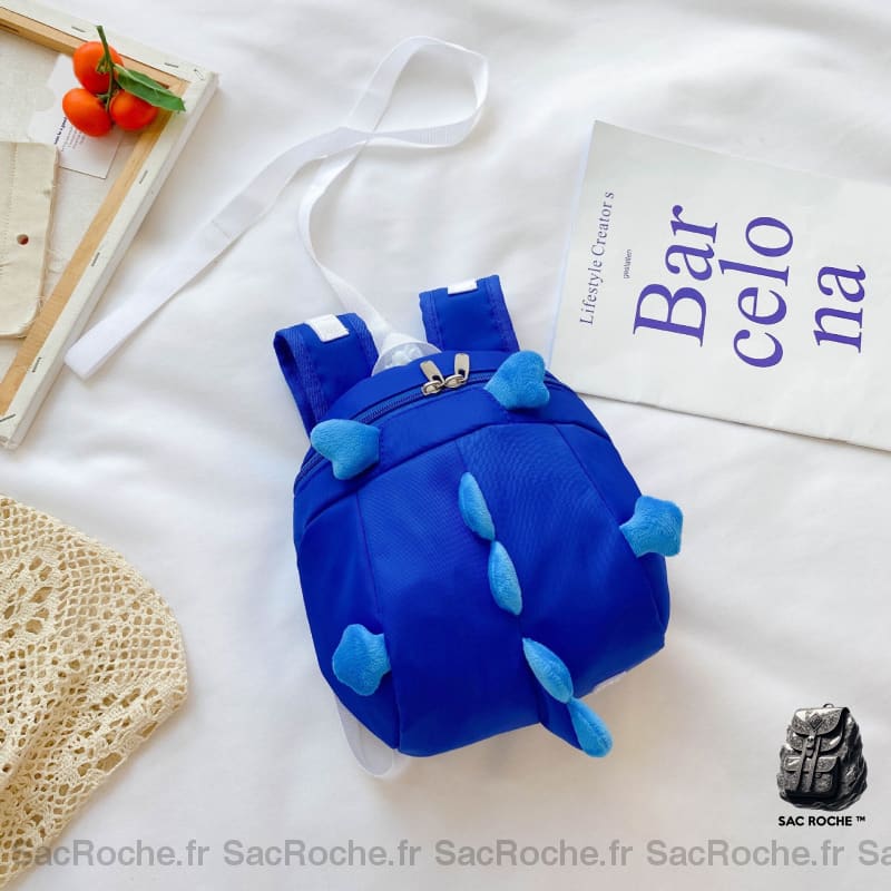 Sac à dos préscolaire forme dinosaure bleu avec un fond, un lit blanc, un poster avec des écritures bleus