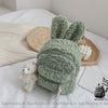 Sac à dos enfant tout doux lapin vert avec un fond un lit blanc, un livre, un petit ourson