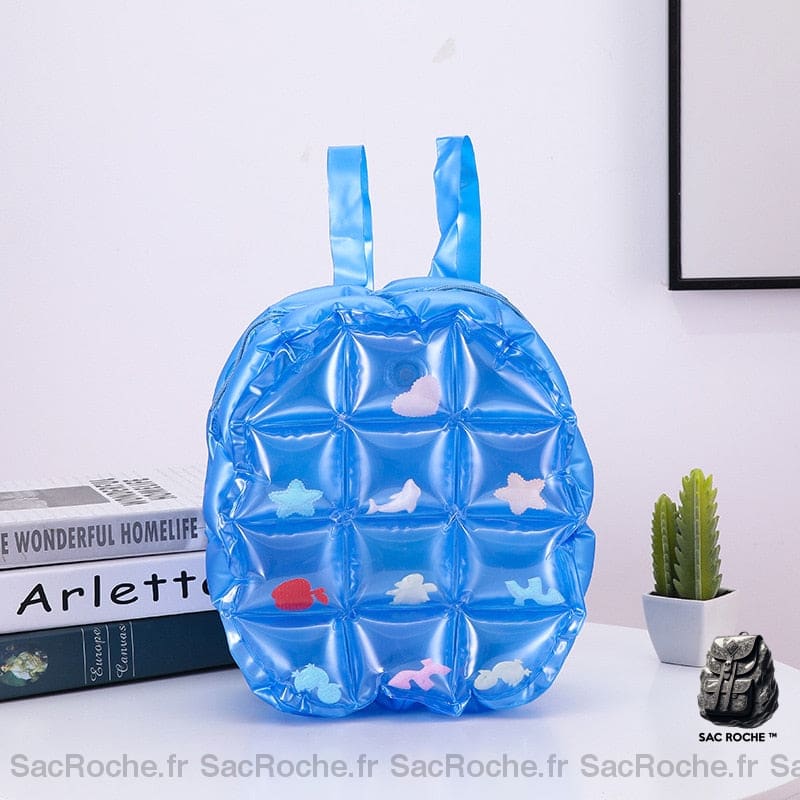 Sac à dos gonflable parfait pour la rentrée en maternelle bleue avec un petit pot et cactus à l'intérieur et des livres sur une table dans une maison