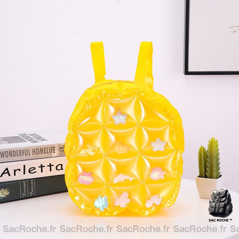 Sac à dos gonflable jaune sur une table avec des livres et un cactus