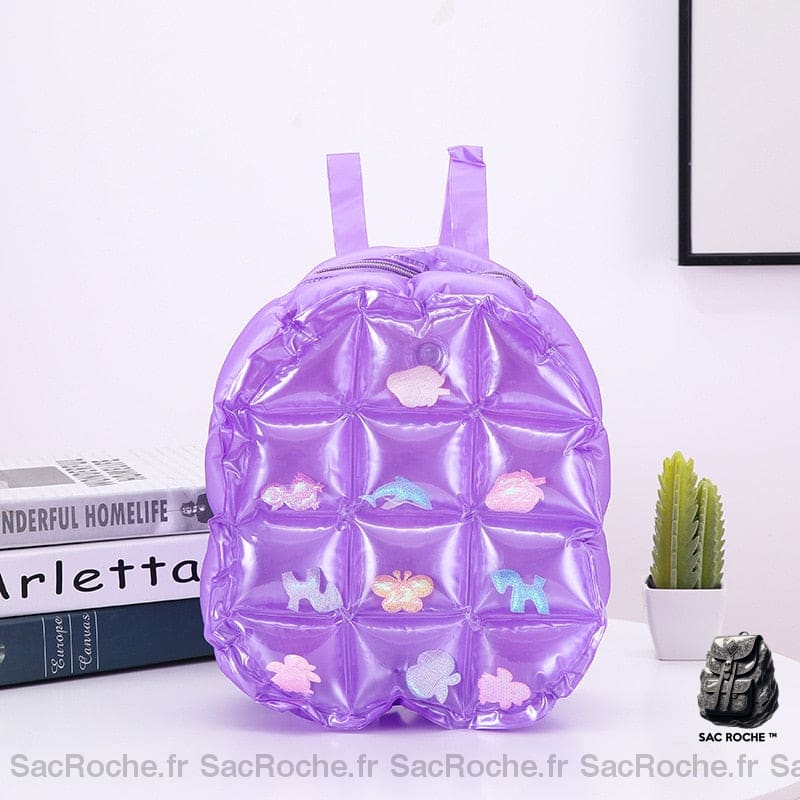 Sac à dos gonflable violet sur une table avec un livre et cactus