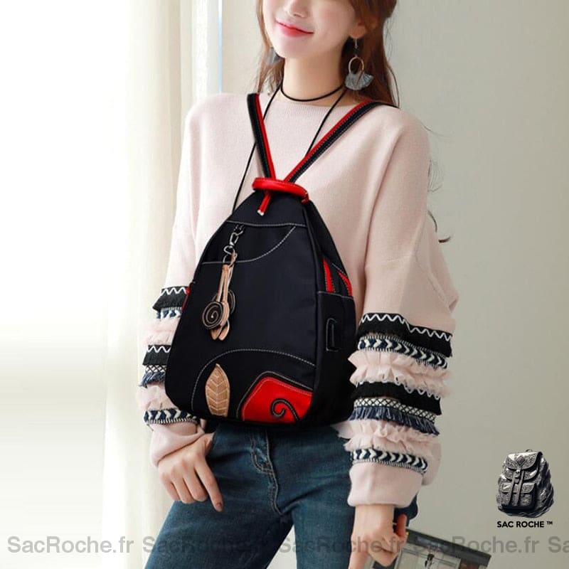 Sac à dos noir et rouge style rétro en nylon porté par une femme devant une fenêtre