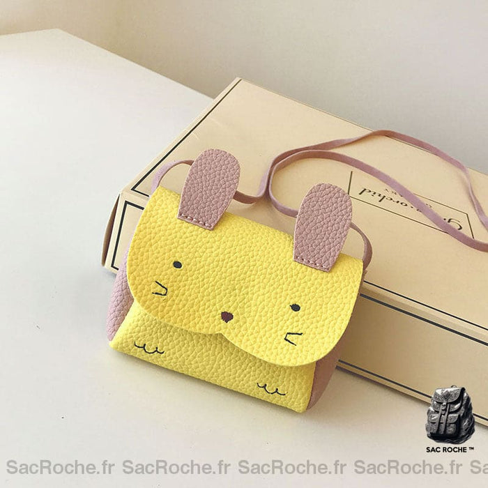 Un petit sac cartable jaune posé à côté d'une boite sur un meuble blanc.