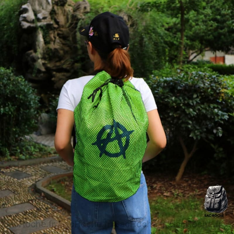 Sac de plage en maille vert avec un fond un jardin et une femme qui porte le sac